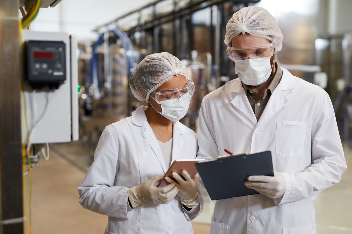 Kvalitetskontrol i fødevareproduktion – to medarbejdere i laboratorietøj