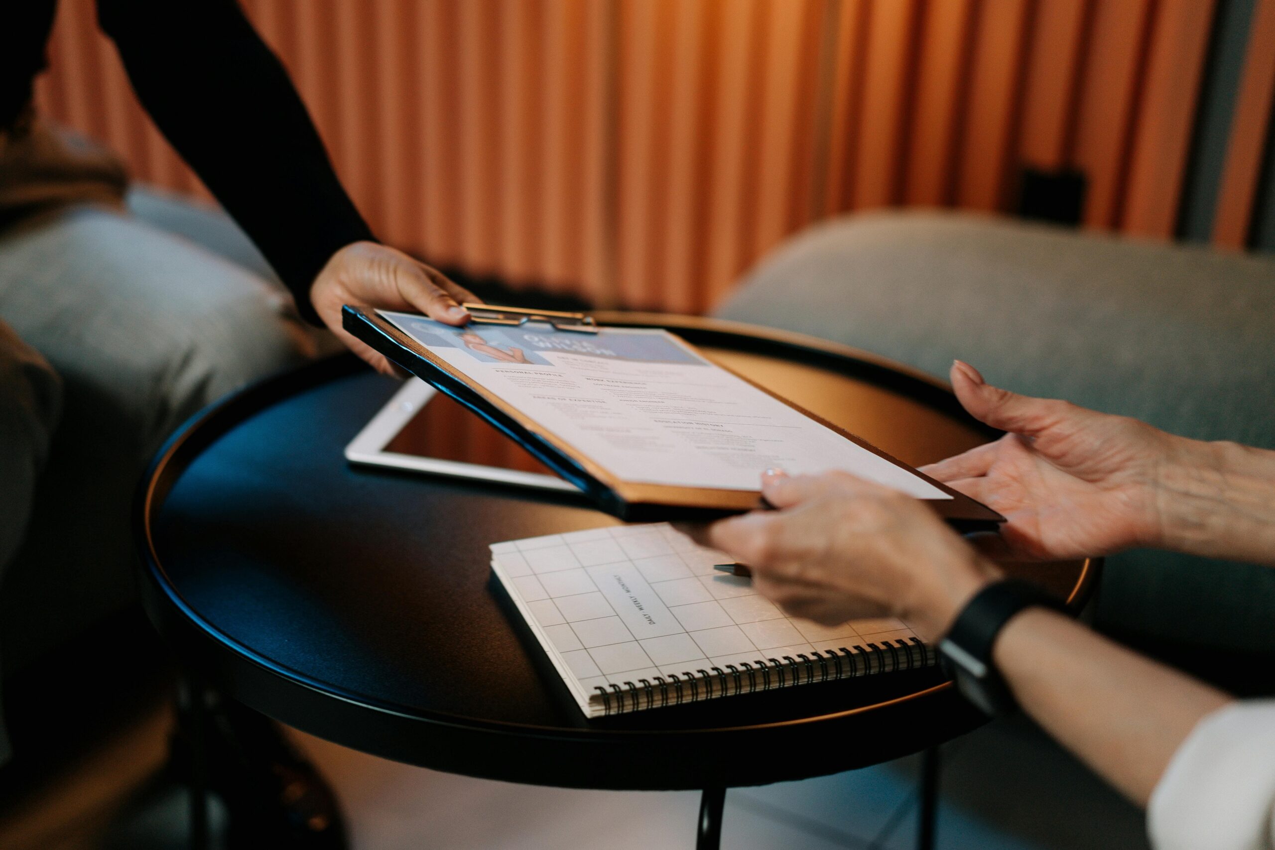 Person afleverer CV på clipboard under samtale